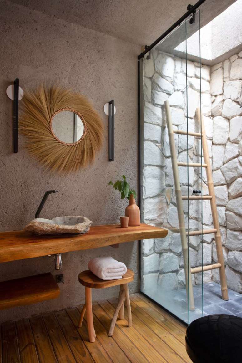 Chalé de praia de 60 m² tem decoração rústica e banheiro com claraboia. Projeto de Roby Macedo Arquitetura. Na foto, parede de pedra, bancada de madeira, cuba de pedra solta.