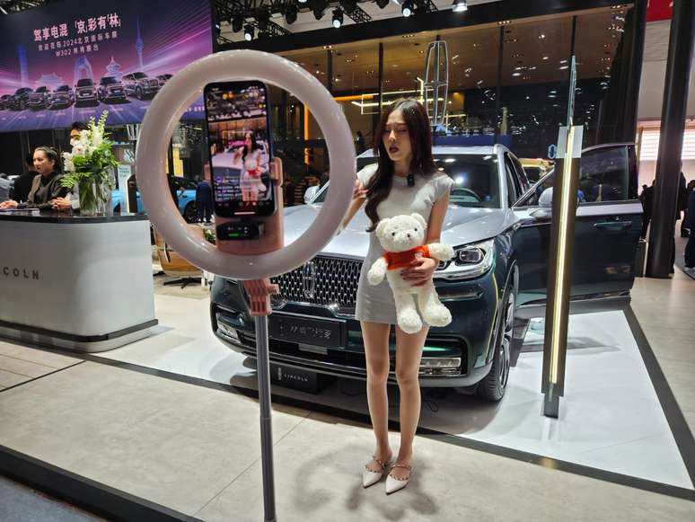 Mulher chinesa faz transmiss&atilde;o para m&iacute;dia social no Auto China 2024