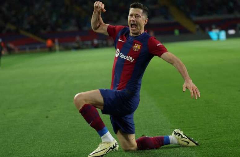 Lluis Gene/AFP via Getty Images - Legenda: Lewandowski em disputa de bola com jogadores do Valencia -
