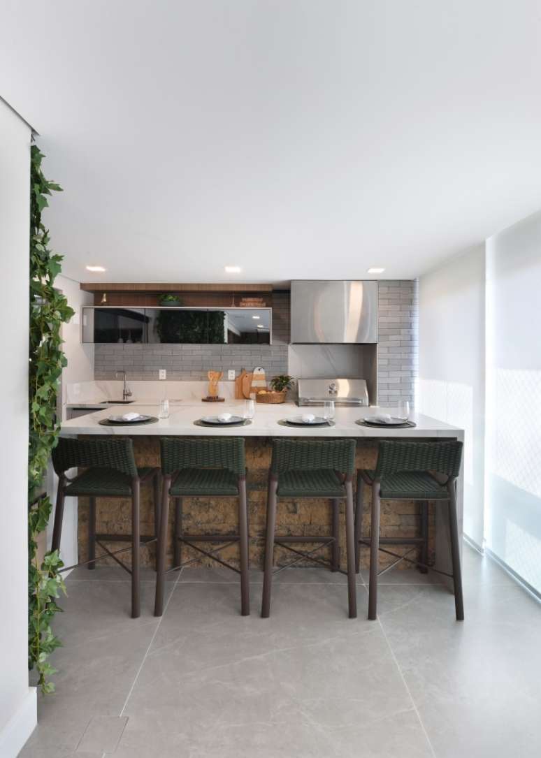 Varanda de estar gourmet é destaque em apartamento de 204 m². Projeto de Rosangela Pena. Na foto, ilha, bancada branca, jardim vertical, churrasqueira.