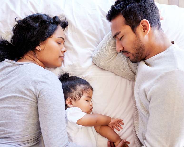Imagem meramente ilustrativa de pais compartilhando a cama com uma bebê