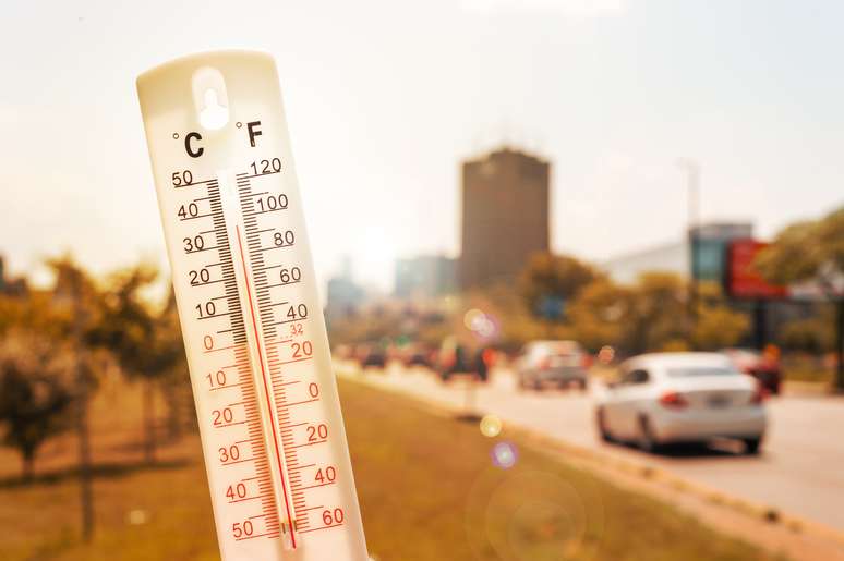 Termômetro na frente dos carros e do tráfego durante a onda de calor