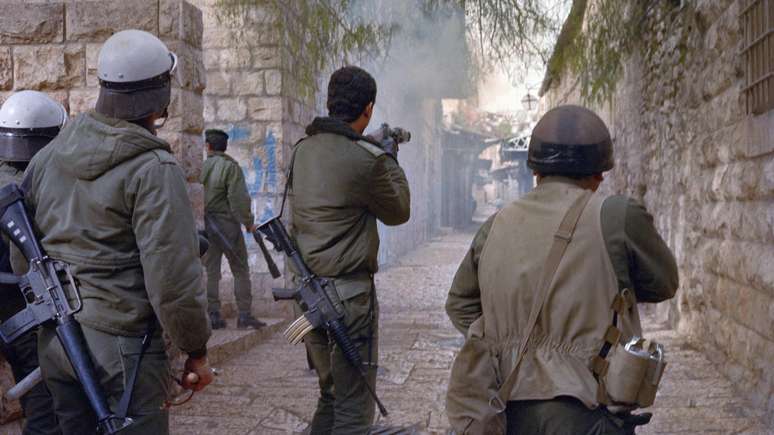 A polícia israelense dispara gás lacrimogêneo contra manifestantes palestinos durante confrontos, em 22 de janeiro de 1988, nas ruas de Jerusalém