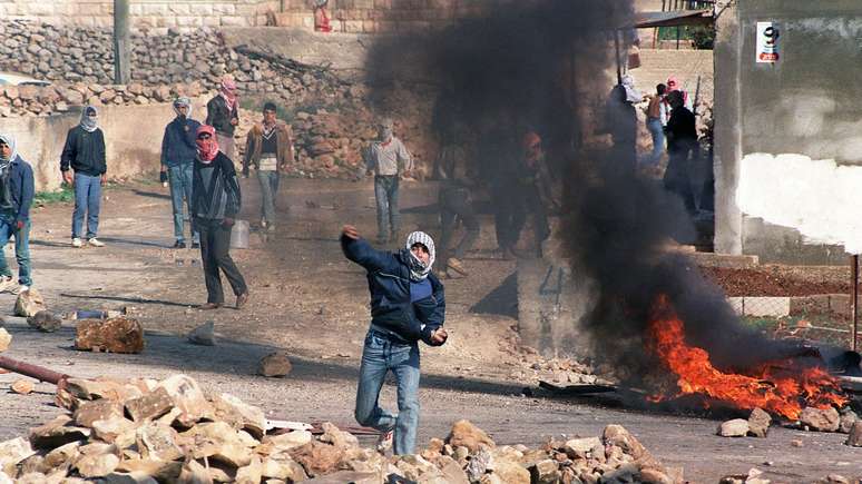 Manifestantes palestinos atiram pedras contra a polícia de choque israelense na vila de Hizme, em Jerusalém em 21 de dezembro de 1987. Essa data foi declarada como o 'Dia da Paz', em apoio aos palestinos nos territórios ocupados por Israel