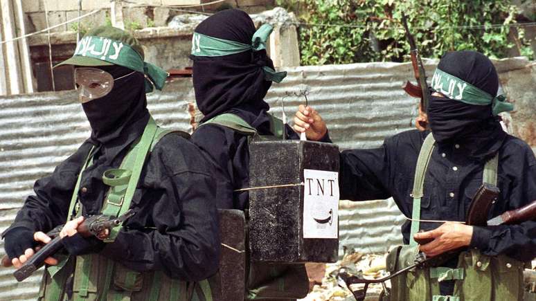 Um militante palestino amarra caixas, marcadas como explosivos TNT, nas costas de um de seus companheiros, aparentemente como um sinal de que estão preparados para realizar atentados suicidas. Foto foi registrada durante um protesto no campo de refugiados palestinos de Ain al-Hilweh, nos arredores do porto de Sidon, sul do Líbano, em outubro de 2000