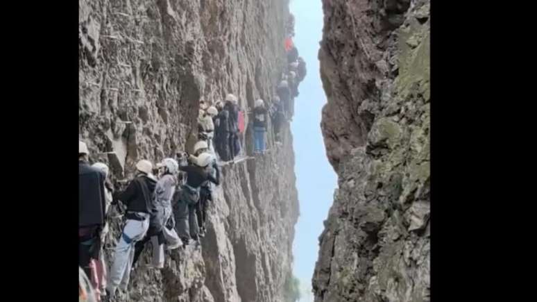 Alpinistas suspensos em montanha na China