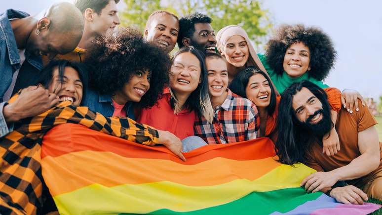 Jovens segurando a bandeira da comunidade LGBTQIAPN+.