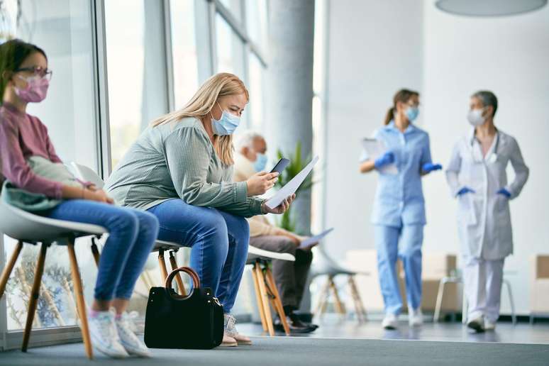 Pacientes de máscara em sala de espera de hospital