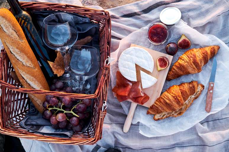 Uma cesta que seria perfeita para presentear uma mãe, com pães, queijo e vinho. 