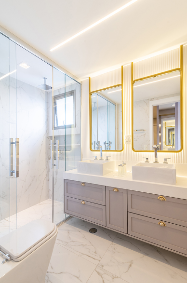 19. Banheiro marmorizado com detalhes dourados criam um espaço luxuoso – Projeto: Mari Milani + Arquitetas | Foto: Julia Herman
