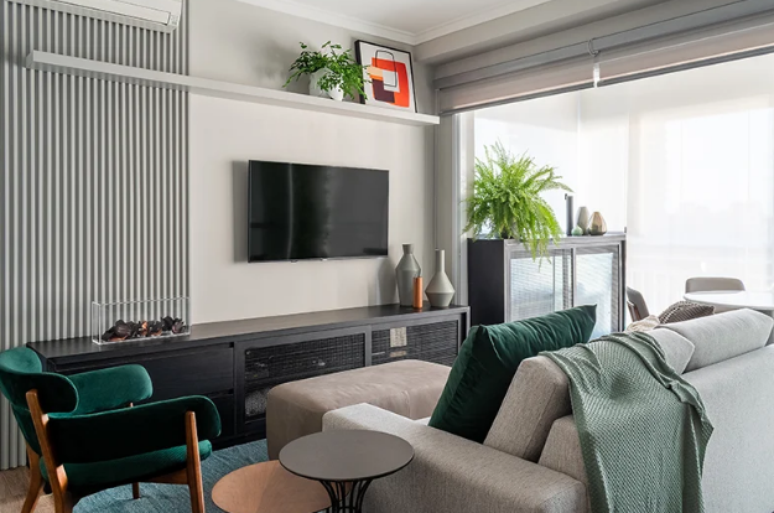 A poltrona verde esmeralda acrescenta um toque de sofisticação e contraste vibrante a esta sala de estar pequena e moderna – Projeto: Mageste & Blinovas Arquitetura | Foto: Julia Novoa