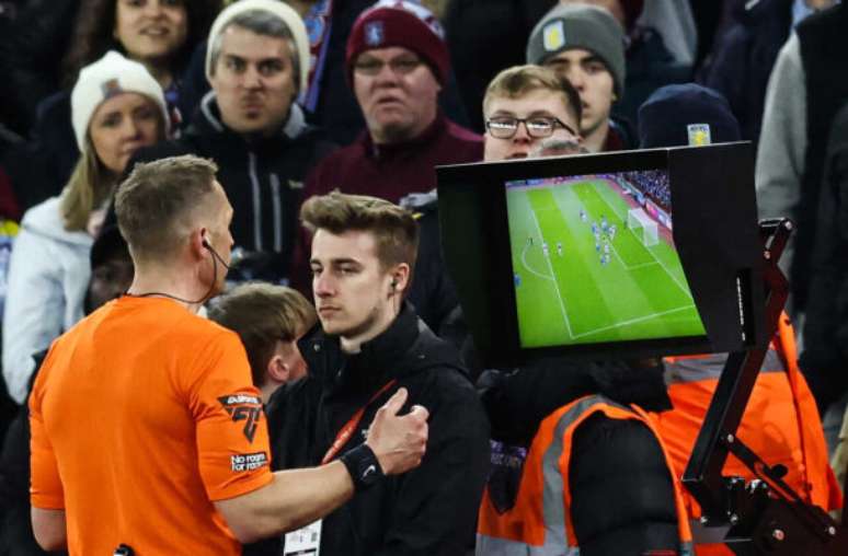 Darren Staples/AFP via Getty Images - Legenda: Árbitro Craig Pawson observa monitor do VAR durante partida entre Chelsea e Aston Villa -