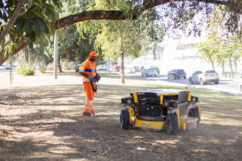 Controlado à distância, robô roçador executa o trabalho com rapidez. Gari fica atento para evitar obstáculos à máquina