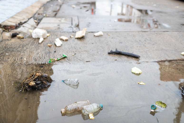 Lixo flutua na superfície da água após chuva forte e inundação