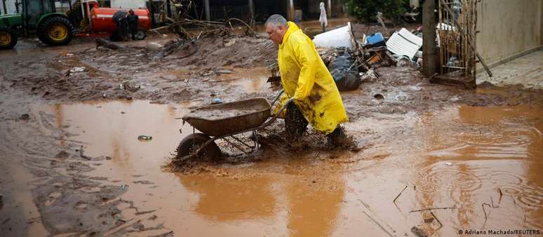 Homem limpa casa inundada em Muçum; contato com a água ou lama em enchentes pode causar doenças