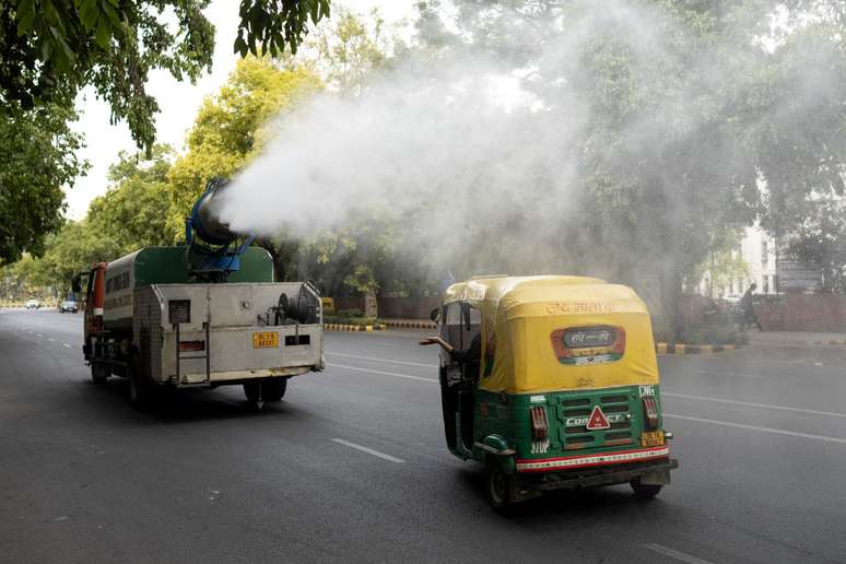 Um caminhão municipal borrifa água em uma estrada para aliviar a onda de calor em curso, em um dia quente de verão em Nova Delhi, Índia, em 29 de maio de 2024.