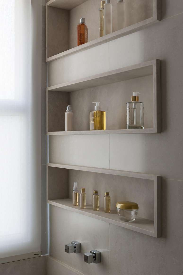 Neste banheiro projetado pela arquiteta Cristiane Schiavoni, o nicho foi esculpido dentro da estrutura do box abrindo espa&ccedil;o para acomodar produtos para o cabelo e corpo, o que tornou o ambiente pr&aacute;tico e elegante.