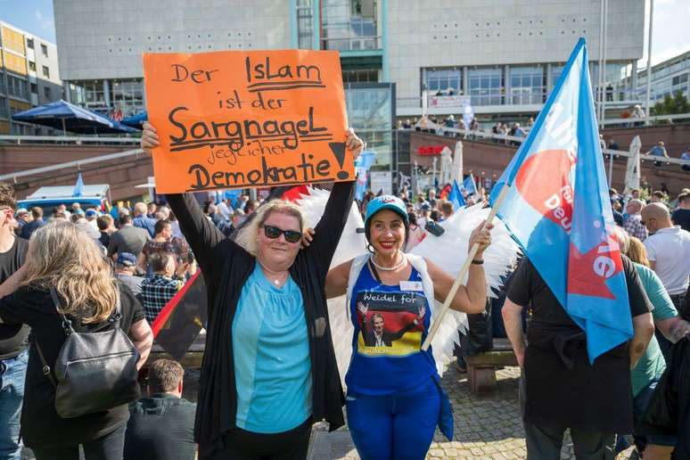 Apoiadora do partido de direita AfD segura um cartaz que diz 'O islã é o prego no caixão da democracia'