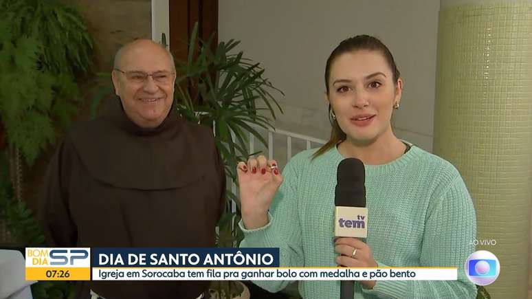 Isabela Sabéllico segurando a medalha de Santo Antônio, ao lado do frei Gilberto Piscitelli, responsável pelo 'bolo do desencalhe'