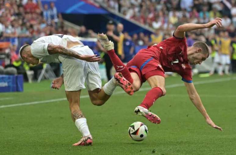 O esloveno Sesko, de branco, divide com Pavlovic.  O goleador passou em branco mas a sua seleção vence a Sérvia por 1 a 0 e vai muito bem no Grupo C da Euro –