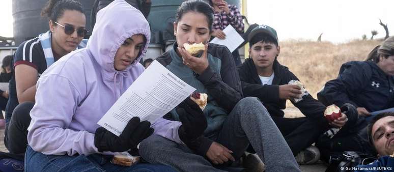 Migrantes equatorianos leem folheto informativo após cruzarem fronteira dos EUA com o México