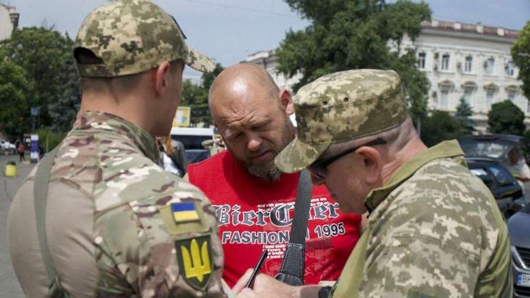 Os oficiais de recrutamento Anatoliy (à direita) e Oleksiy estão parando homens nas ruas de Odessa para checar se eles se registraram, de acordo com a nova lei