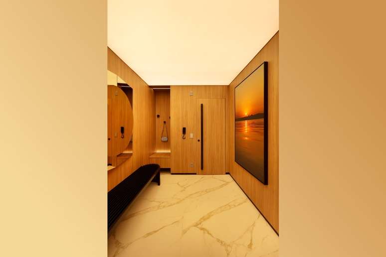 No hall de entrada, o escritório Spaço Interior combinou madeira nas portas e paredes com um piso marmorizado, criando um ambiente convidativo e sofisticado 