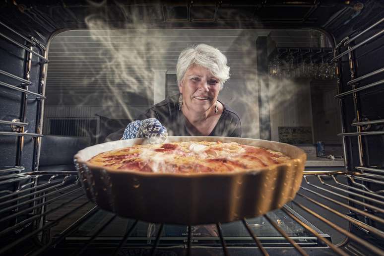 Mulher retira assadeira do forno