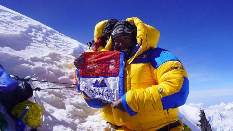 Tshiring Jangbu Sherpa exibe orgulhosamente uma bandeira da campanha de limpeza da montanha