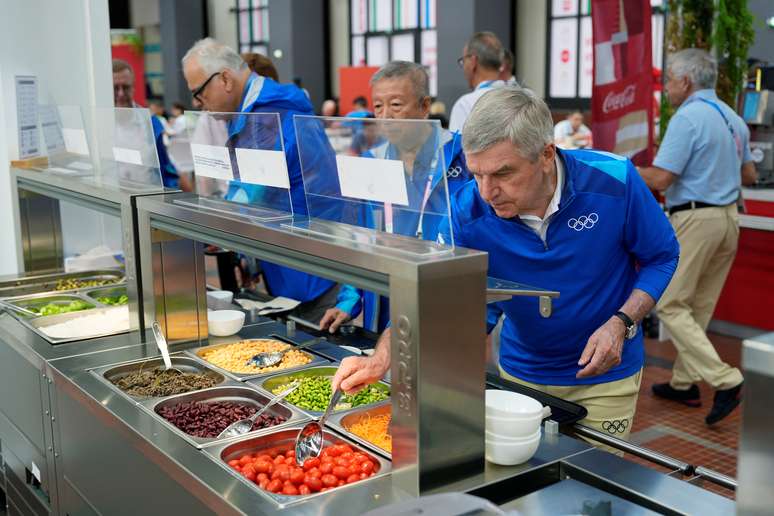 O presidente do Comitê Olímpico Internacional, Thomas Bach, faz refeição no refeitório dos atletas na Vila Olímpica, em Paris