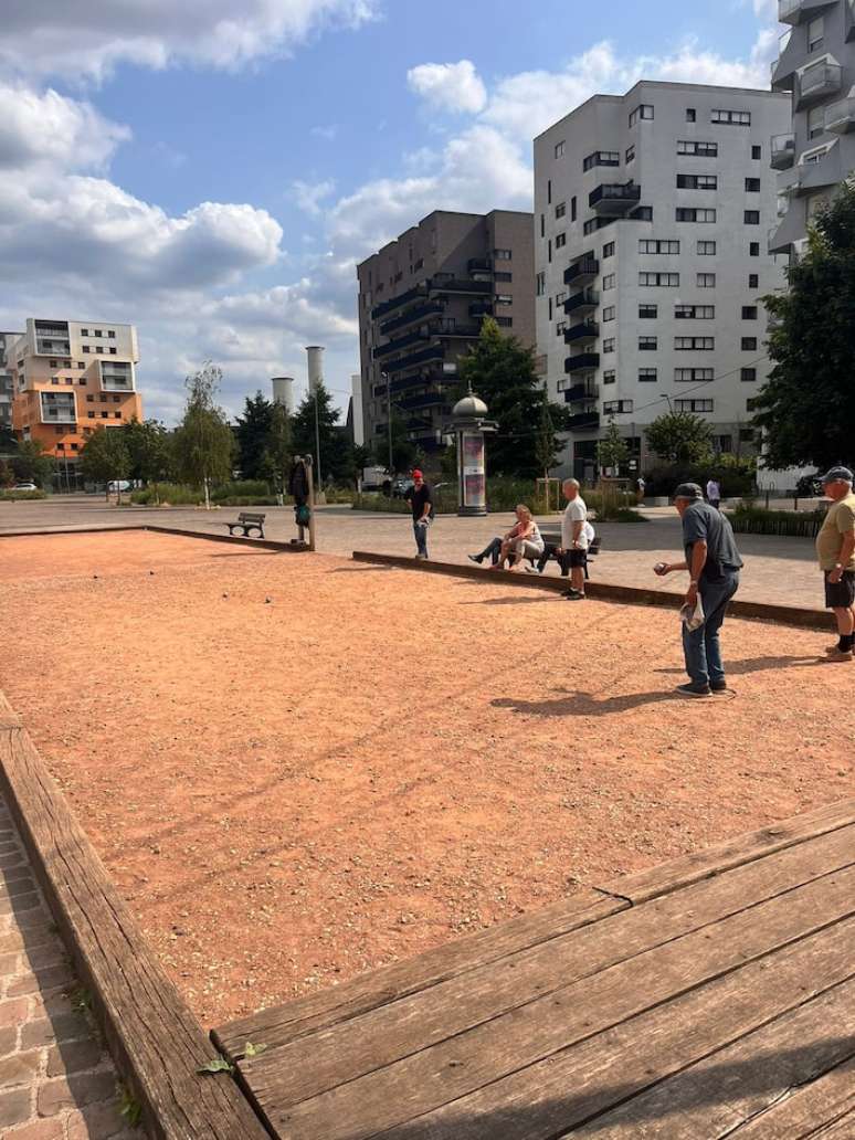 Adultos e idosos jogam petanca, semelhante à bocha, em parque de Saint-Ouen.