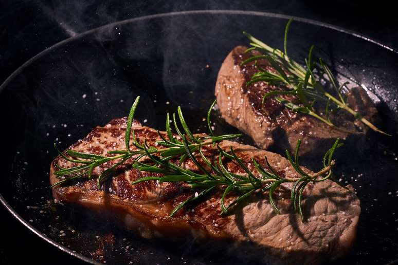 Pedaço de carne sendo preparado na frigideira