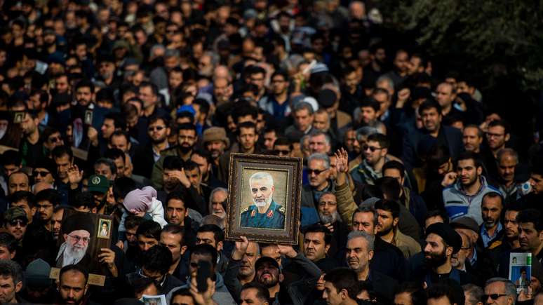 Manifestantes seguram uma imagem do comandante iraniano Qassem Soleimani após o ataque aéreo dos EUA no Iraque que o matou