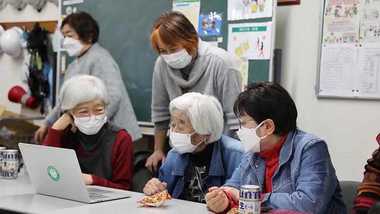 Tomoko Okayama (atrás) conversa com moradores do complexo de apartamentos Sky Heights sobre a organização da geladeira e o desperdício de alimentos