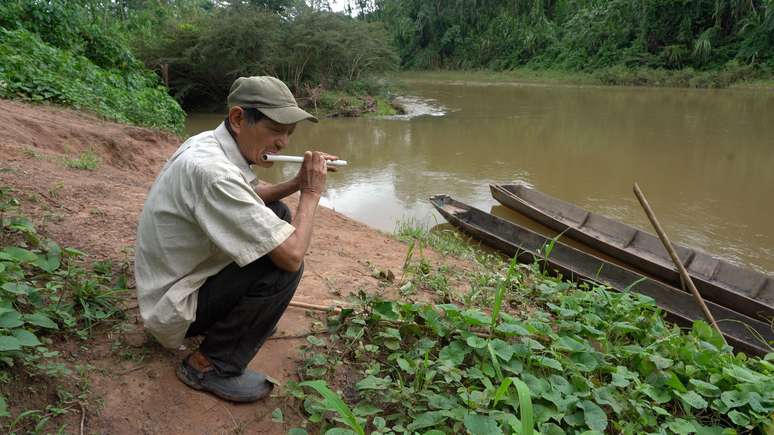 Fermín toca flauta em frente ao rio Maniqui, sua principal fonte de alimento