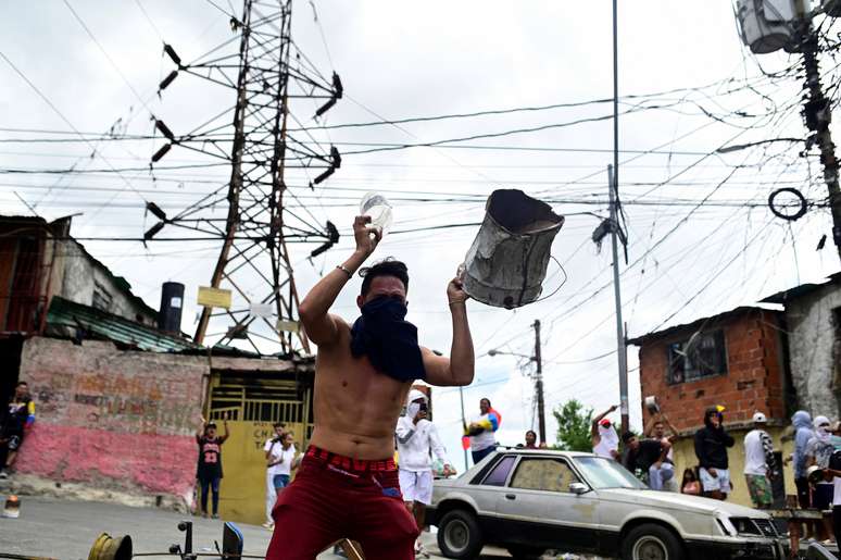 Um homem segura um tanque de metal enquanto moradores batem panelas para protestar contra os resultados das eleições depois que o presidente Nicolás Maduro e seu rival da oposição Edmundo Gonzalez reivindicaram a vitória na eleição presidencial de domingo, no bairro de Los Magallanes de Catia, em Caracas, Venezuela , em 29 de julho de 2024.