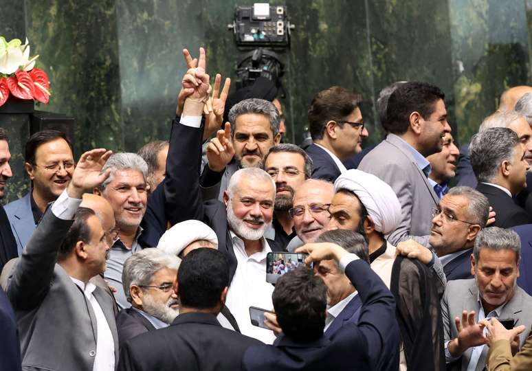 No centro da imagem, Ismail Haniyeh aparece cercado por políticos iranianos no parlamento iraniano em Teerã, Irã, em 30 de julho de 2024