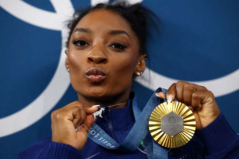 Medalhista de ouro, Simone Biles, dos Estados Unidos, celebra a medalha e mostra colar de cabra