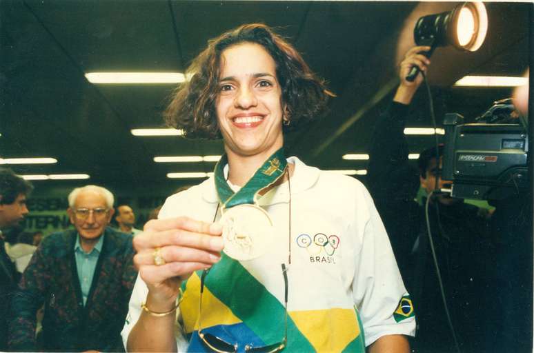 Virna mostra a medalha de bronze conquistada pela seleção feminina de vôlei em Atlanta-96.