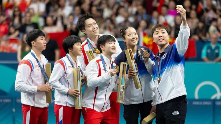 Medalhistas de tênis de mesa da Coreia do Norte, da Coreia do Sul e da China tiram selfie em pódio