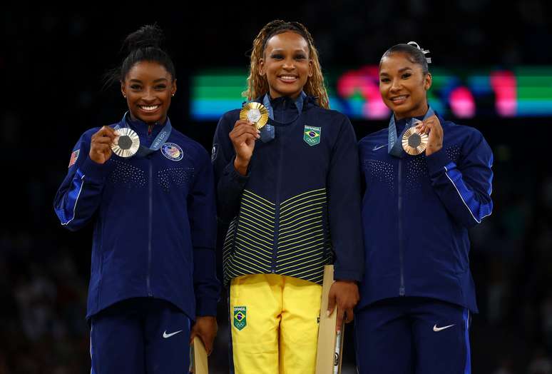 A medalhista de ouro Rebeca Andrade, do Brasil, comemora no pódio com a medalhista de prata Simone Biles, dos Estados Unidos, e a medalhista de bronze Jordan Chiles, dos Estados Unidos. 