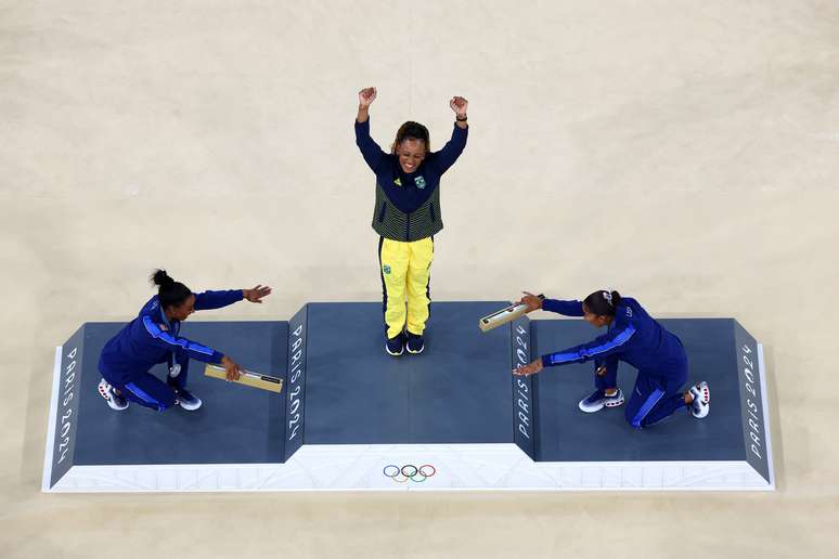 A medalhista de ouro Rebeca Andrade, do Brasil, comemora com a medalhista de prata Simone Biles, dos Estados Unidos, e a medalhista de bronze Jordan Chiles, dos Estados Unidos, no pódio. 