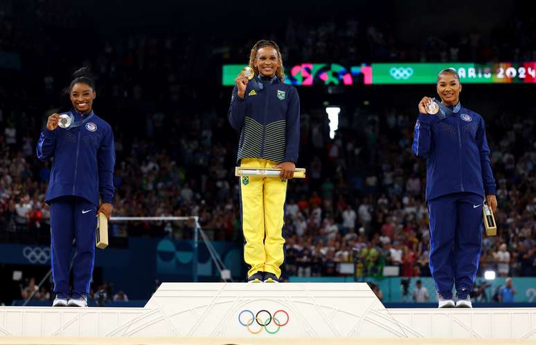 Medalhista de ouro Rebeca Andrade, do Brasil, comemora no pódio com a medalhista de prata Simone Biles, dos EUA, e a medalhista de bronze, Jordan Chiles, também dos EUA