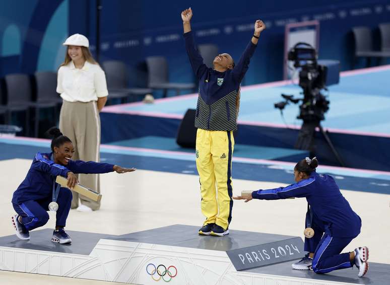 Rebeca Andrade comemora no pódio ao lado de Simone Biles e Jordan Chiles