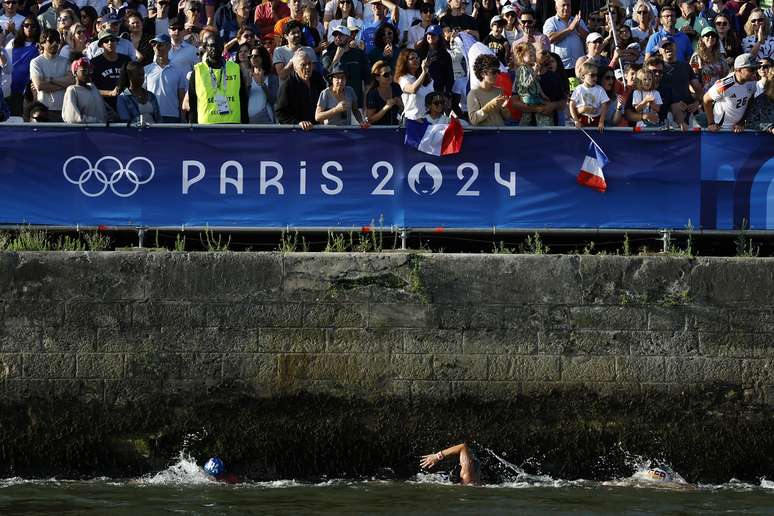 Nadadores da maratona aqu&aacute;tica perto de uma sa&iacute;da de esgoto