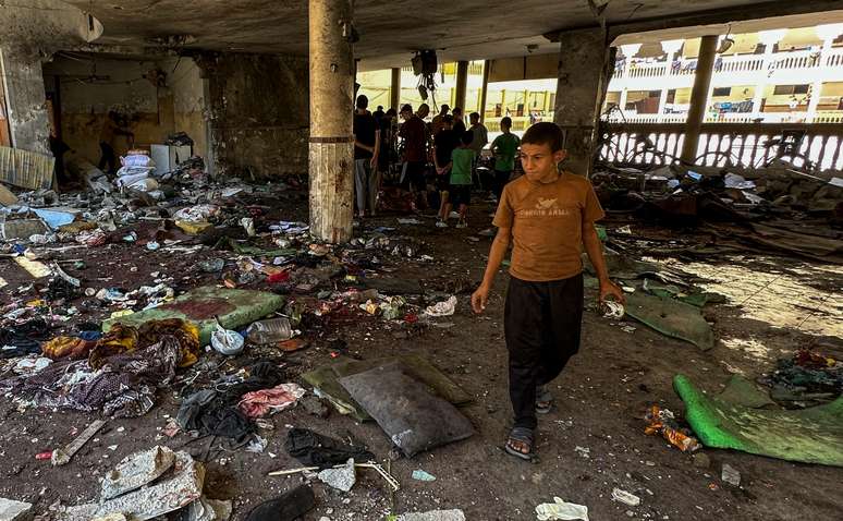 Palestinos observam os danos no local de um ataque israelense a uma escola que abriga pessoas deslocadas, em meio ao conflito Israel-Hamas, na cidade de Gaza, 10 de agosto de 2024.