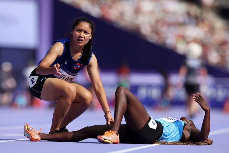A atleta do Laos Pha Aphay ajudou sua colega Lucia Moris, do Sud&atilde;o do Sul, durante uma prova classificat&oacute;ria para os 100 metros femininos