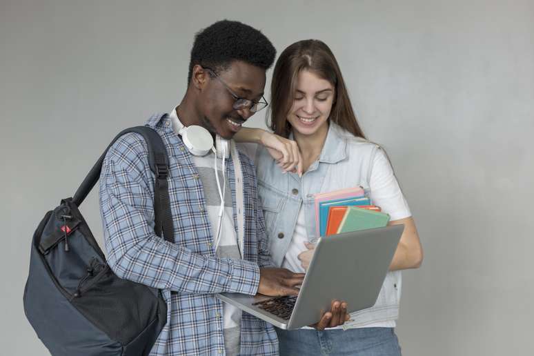 Estudantes com laptop representando como escolher faculdade. 