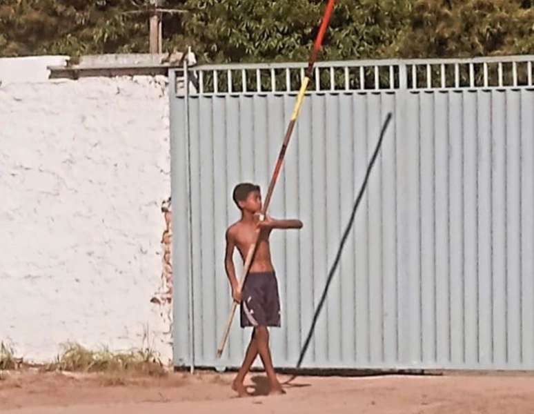 O jovem Moisés treinando com uma vara de madeira no quintal de casa