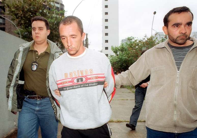 Cristian Cravinhos é escoltado, no dia da reconstituição dos homicídios do casal Richthofen, em novembro de 2002.